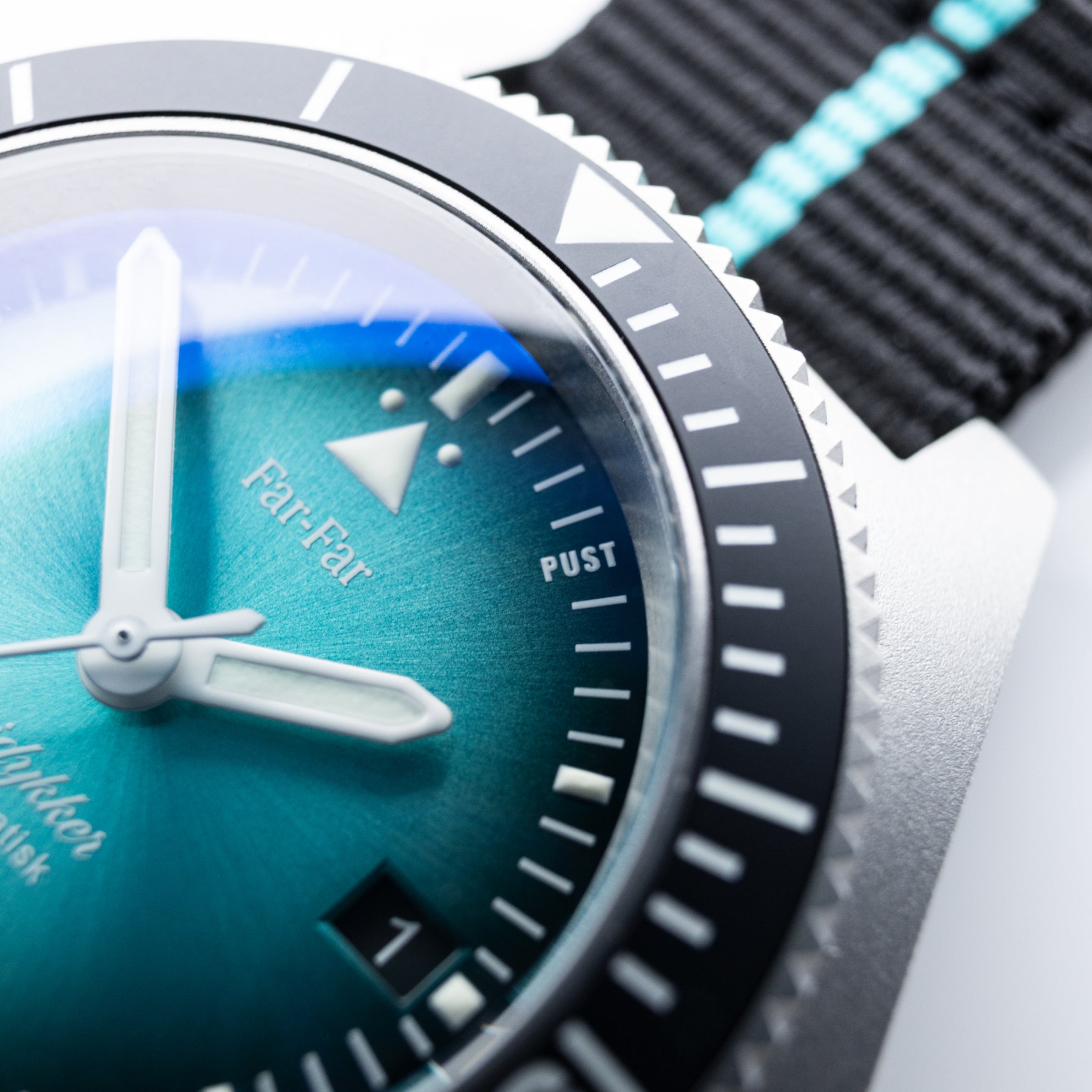 Far-Far Fridykker – detaljbilde av urskive og bezel med turkis solstrålemønster og PUST-markering
